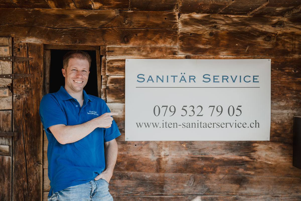 Pius Iten vor einer Holzhütte, daneben ein Schild mit seiner Telefonnummer
